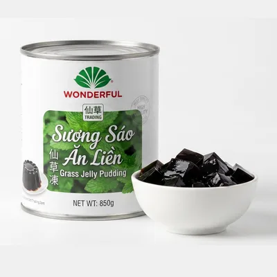Wonderful can with a green label reading Sương Sáo Ăn Liền, grass jelly pudding, 850 grams, beside a white bowl of black jelly cubes.